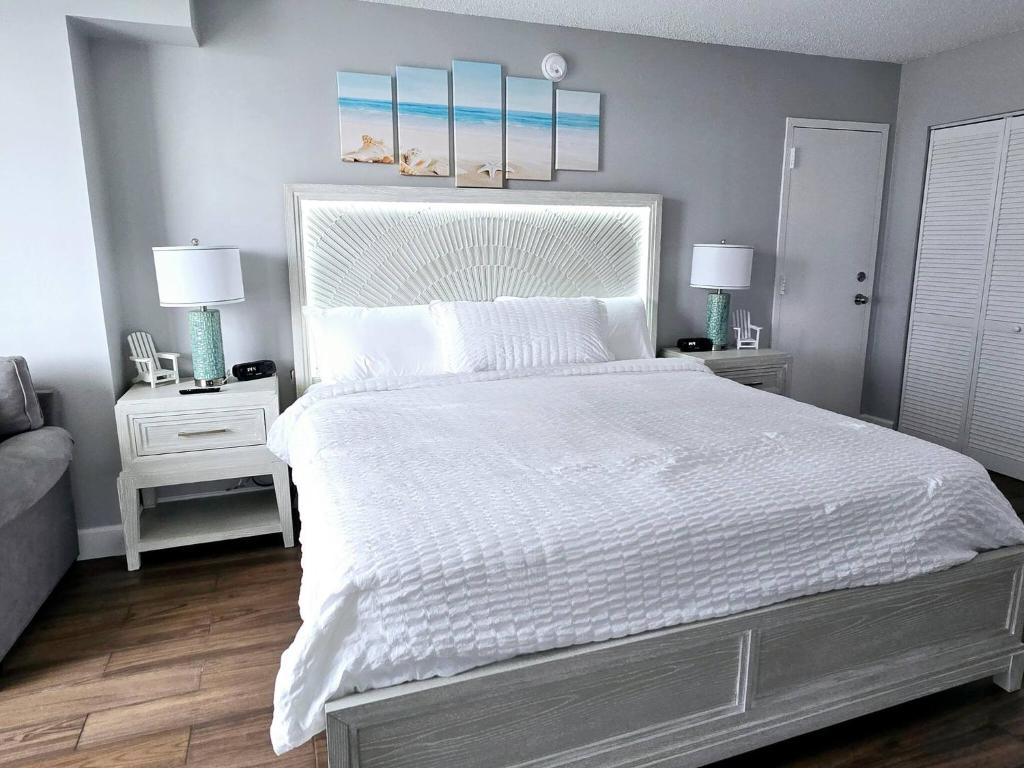 デイトナビーチにある3 Oceanview Studios connecting w/pool, tiki barのベッドルーム1室(白い大型ベッド1台、ナイトスタンド2台付)