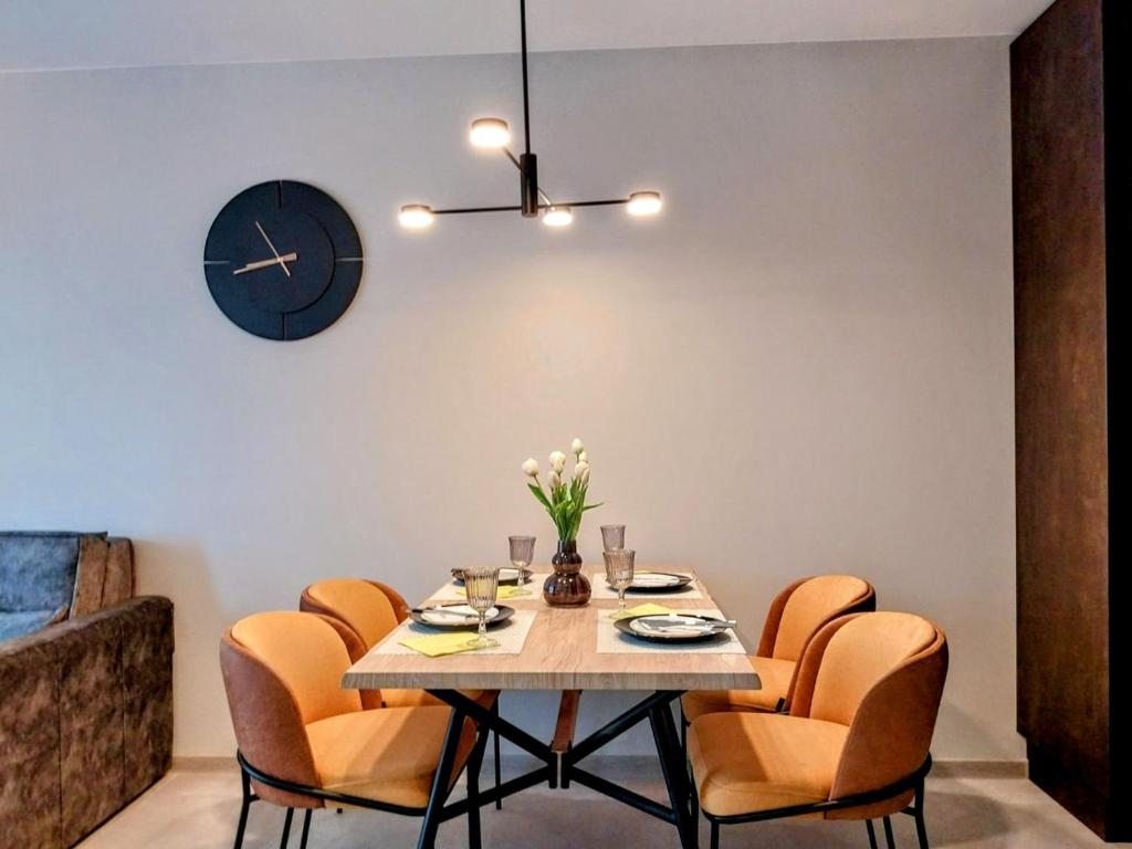 a dining room with a table and chairs and a clock at Ika Delux in Burgas