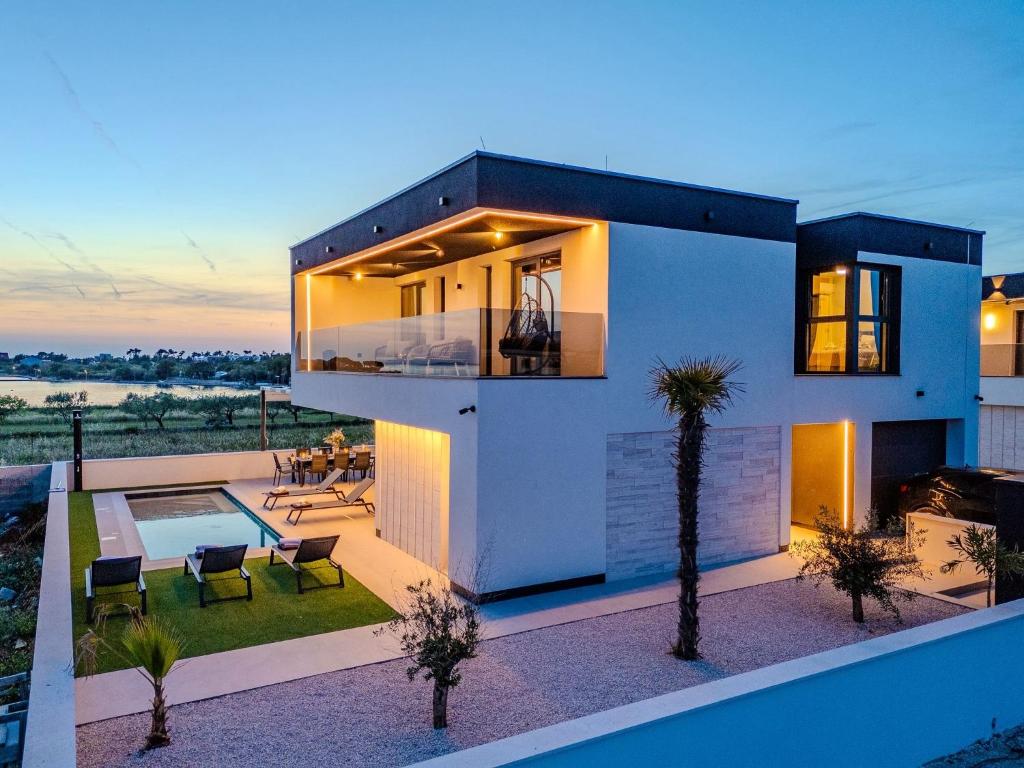 a modern house with a swimming pool at dusk at NEW! Luxury Villa Golden Hour near the beach with heated pool and sauna - TA Leut agency in Privlaka