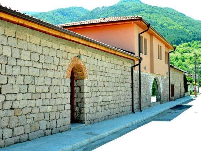 a brick building with an archway next to a street at Yustina VIllas Къща за гости in Ustina