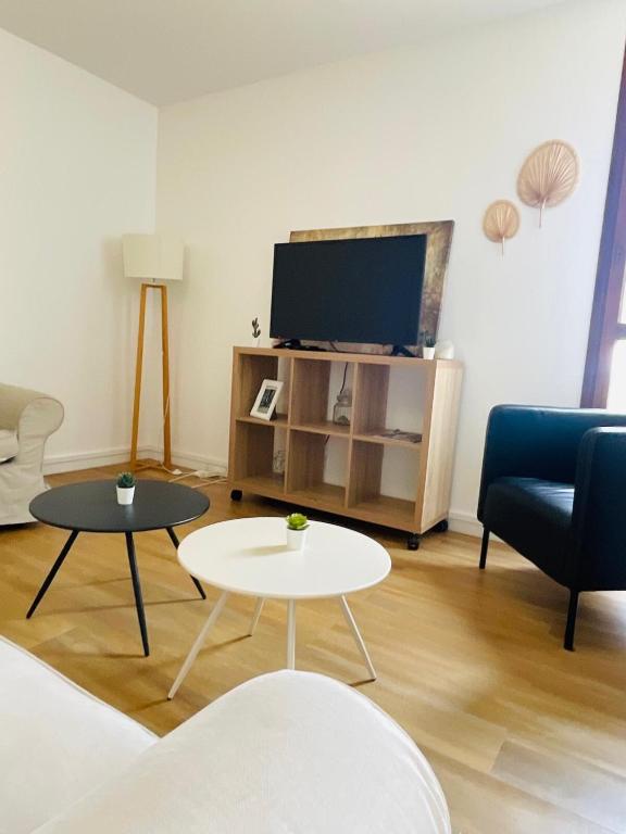 - un salon avec une télévision, un canapé et des tables dans l'établissement Le Repaire Urbain - 8 voyageurs, à Orléans