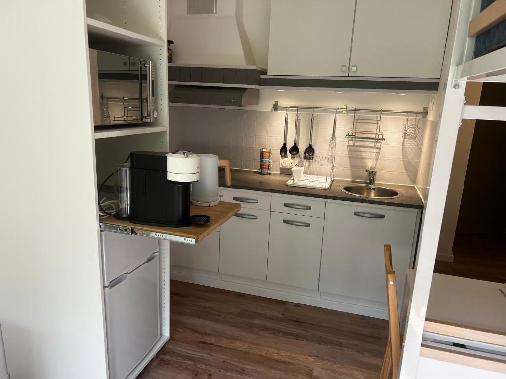 une petite cuisine avec des armoires blanches et un évier dans l'établissement Jolie studio à 200m de la plage principale, à Arcachon
