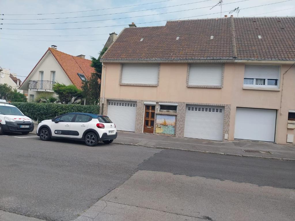 Deux voitures garées sur un parking en face d'une maison dans l'établissement La mer, à Le Portel