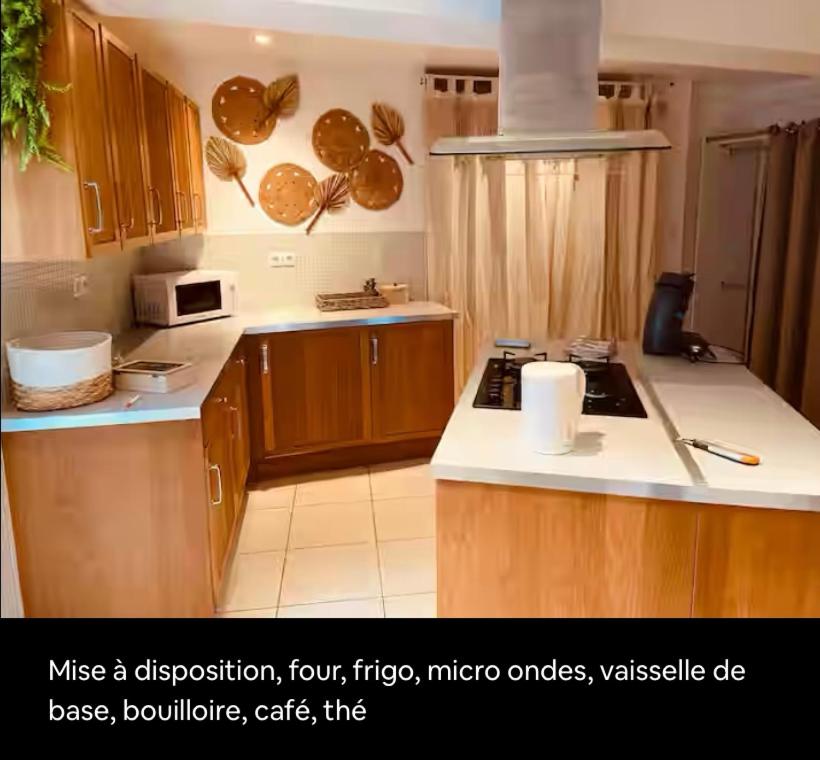 une cuisine avec des placards en bois et des comptoirs blancs dans l'établissement Appartement détente, à Valros