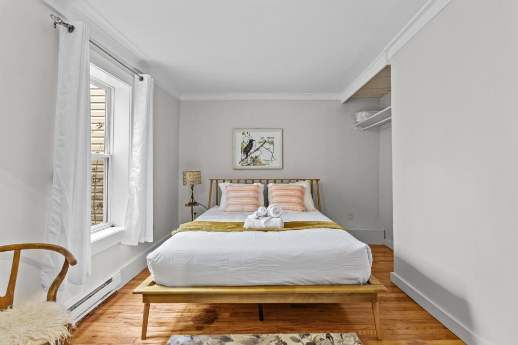 Habitación blanca con cama con almohadas rosas en Bond St Flat 1bd 1bth Zen Garden Central, en St. John's