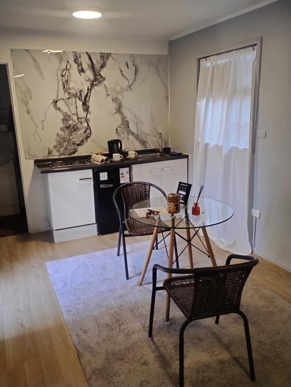 a room with a table and chairs and a kitchen at Beehouse Casa Miel Villa Alemana in Villa Alemana