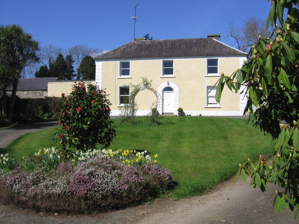 a large white house with flowers in the yard at Ballinclea House Bed and Breakfast in Brittas Bay