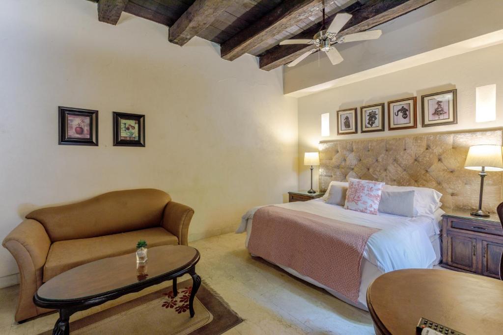 ein Schlafzimmer mit einem Bett, einer Couch und einem Tisch in der Unterkunft Estrella de San Pedro B&B in Cartagena de Indias
