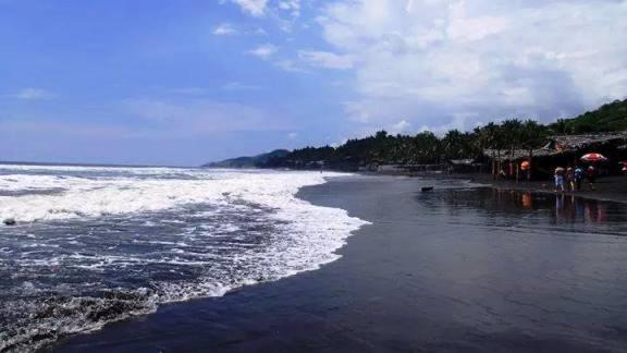 a beach with people standing on the sand and the ocean at AC Rooms-Piscina-Playa El Tunco in La Libertad
