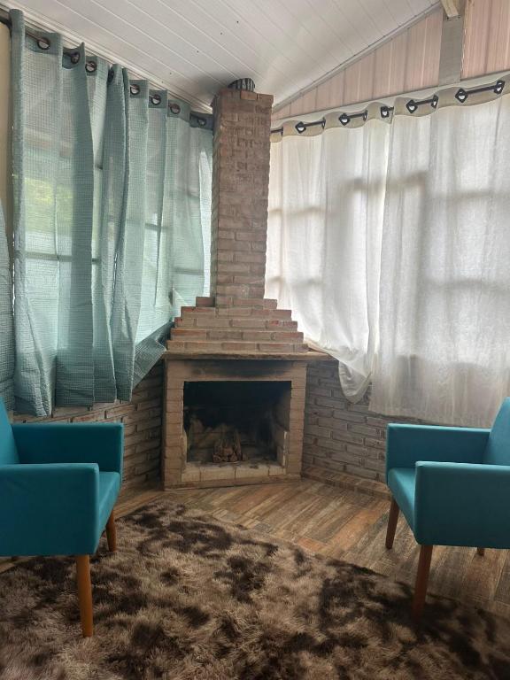 a living room with a fireplace and two blue chairs at Casa Quina da mata in Santo Antônio do Pinhal