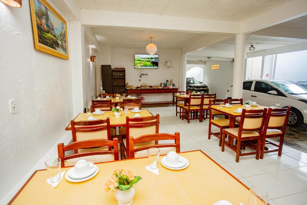 a restaurant with wooden tables and chairs and a car at Pousada dos Girassois Trancoso in Porto Seguro