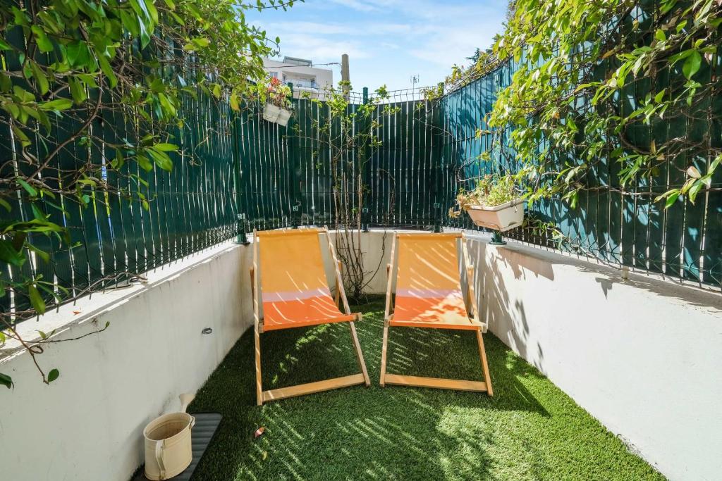 deux chaises assises sur le côté d'une clôture dans l'établissement Apartment with garden near the beach, à Antibes