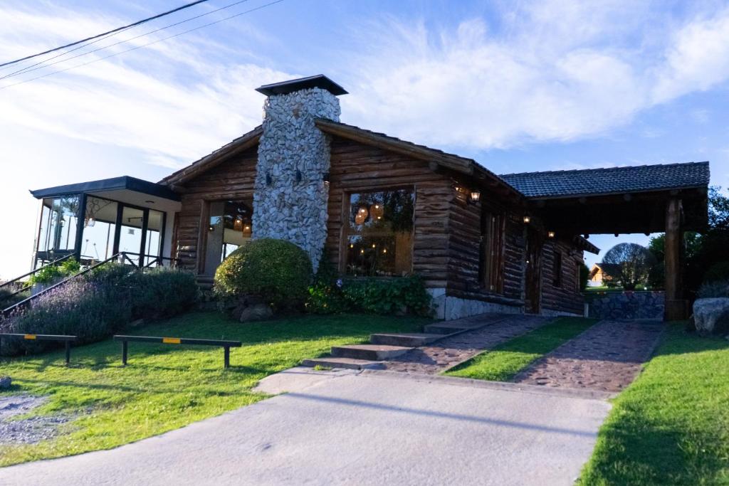 a log house with a stone chimney on the yard at Corazon de la Sierra in Tandil