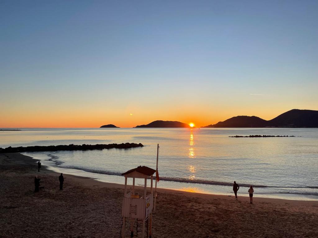 a group of people standing on a beach at sunset at La Gritta in Lerici