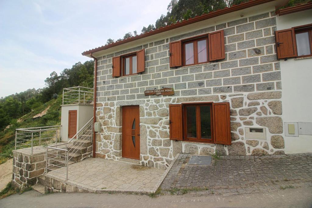 ein Steinhaus mit braunen Türen und einer Treppe in der Unterkunft Casa da Carvalha Mona in Rio Caldo