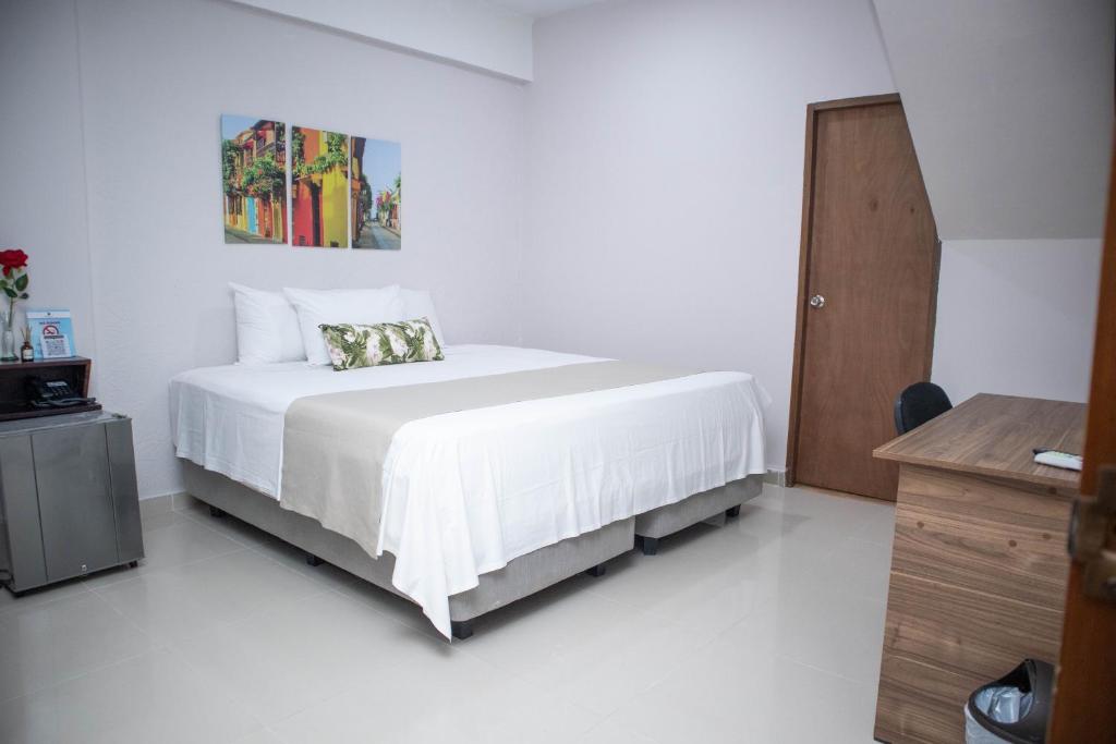 a white bedroom with a bed and a painting on the wall at Hotel El Marqués De Manga in Cartagena de Indias