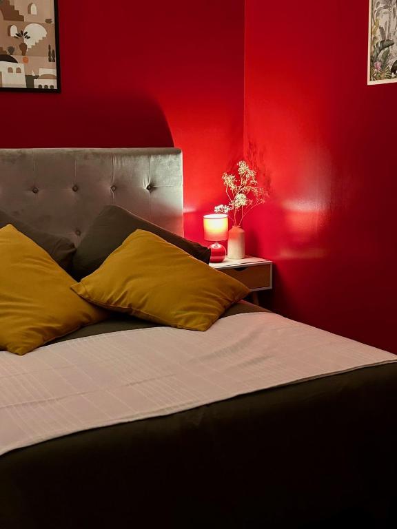 - une chambre avec des murs rouges et un lit avec des oreillers jaunes dans l'établissement Chambre cosy avec petit déjeuner chez Olivier et Manuel à Clavette, proche La Rochelle, à Clavette