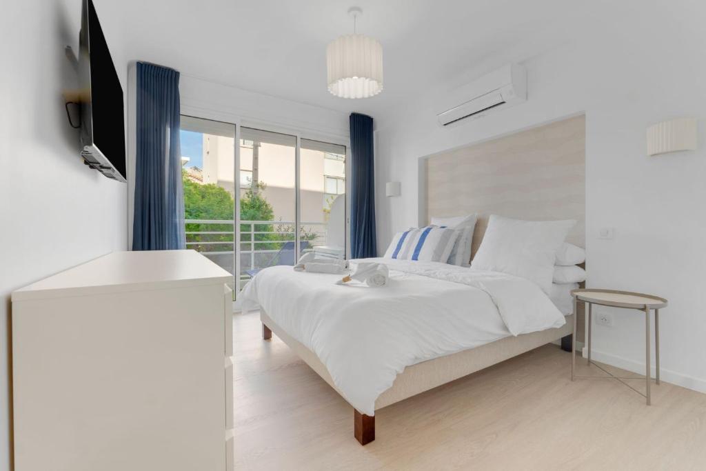 une chambre blanche avec un lit et une télévision dans l'établissement 2-bedroom Royal Beach, à 2minutes de la plage, à Cannes