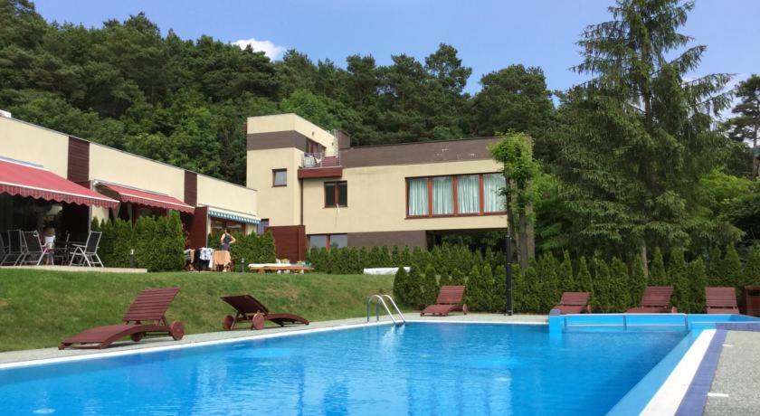 a swimming pool with chairs and a house in the background at Apartament Przy Parku Wisełka in Wisełka