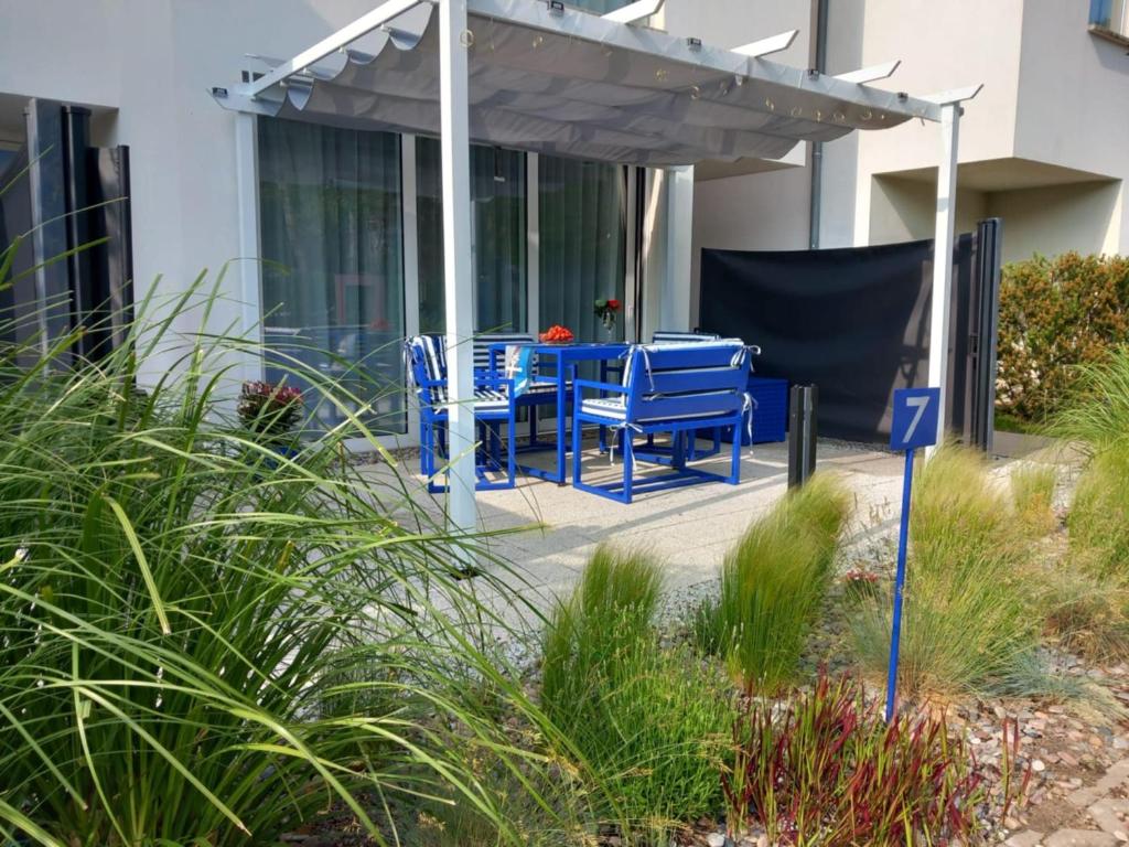 una mesa azul y sillas bajo una pérgola en Apartament Blu Mare Pogorzelica, en Pogorzelica