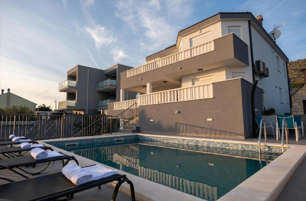 a house with a swimming pool in front of a building at Vila Kathy - kuća za odmor in Seget Vranjica