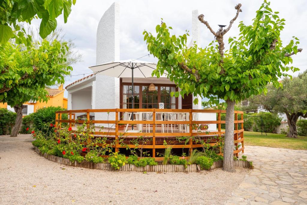 a house with a tree and flowers in front of it at Casa Saona En Riumar ( a 100m de la playa ) in Riumar