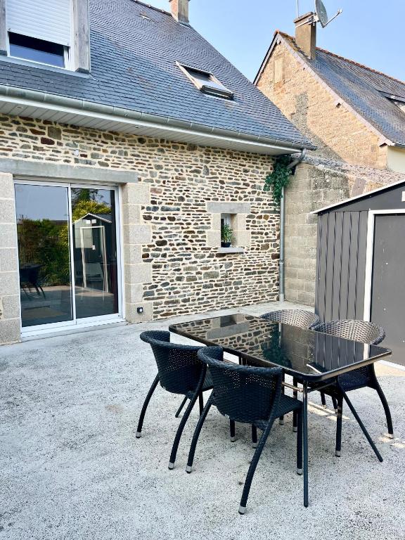 un patio avec une table et des chaises devant un bâtiment dans l'établissement Échappée Belle du Mont-Saint-Michel, à Saint-Georges-de-Gréhaigne