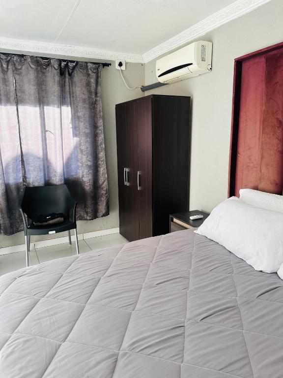 a bedroom with a large bed and a chair at Rose's Lodge in Ga-Selala