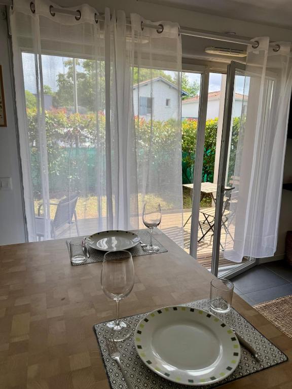 - une table avec une assiette et 2 verres à vin dans l'établissement Modern garden apartment, à Labenne