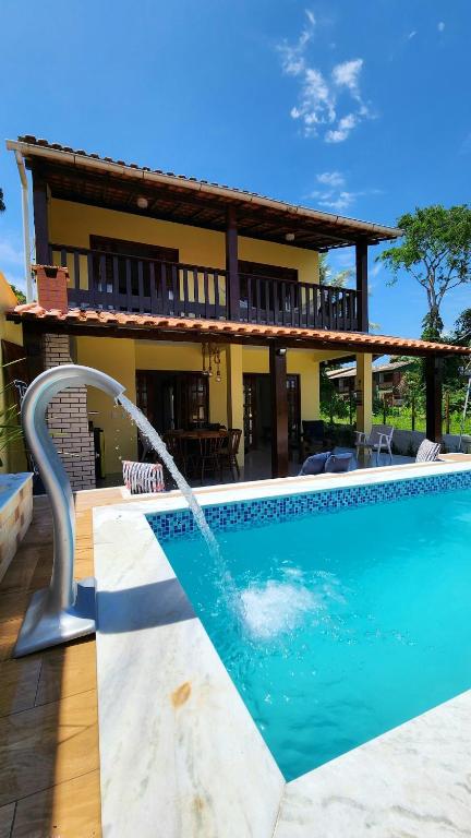 a swimming pool with a water fountain in front of a house at Linda casa com excelente localização em Boipeba in Ilha de Boipeba