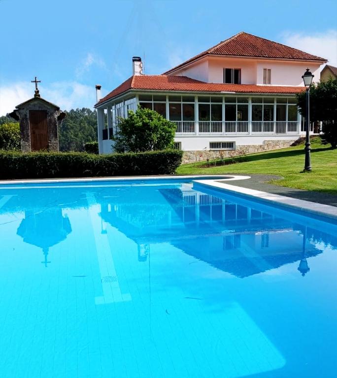 a large blue swimming pool in front of a house at O Retiro de Bernardo in Teo