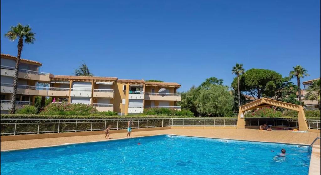 - une piscine en face d'un immeuble dans l'établissement Résidence privée avec balcon, piscine et place de parking, au Lavandou