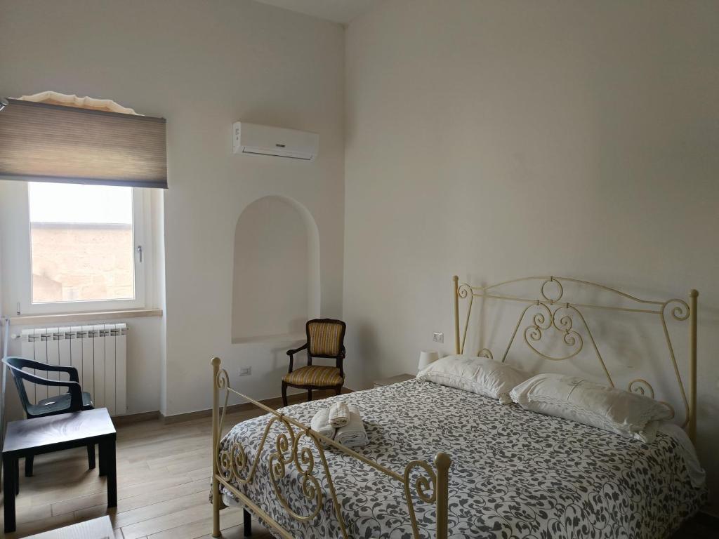 a bedroom with a bed and a chair and a window at Gravina House in Castellaneta