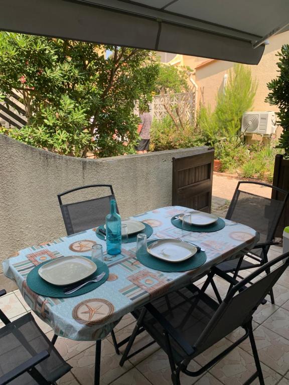 une table avec des assiettes et une bouteille et des chaises dans l'établissement Plage Le Lydia, au Barcarès
