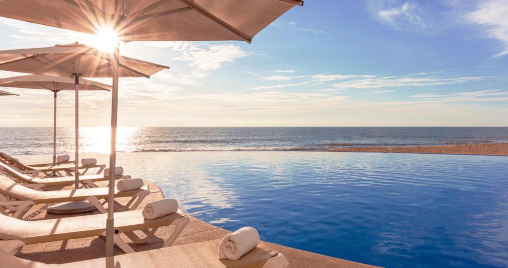 una piscina con sillas y una sombrilla y el océano en Park Royal Beach Mazatlán, en Mazatlán