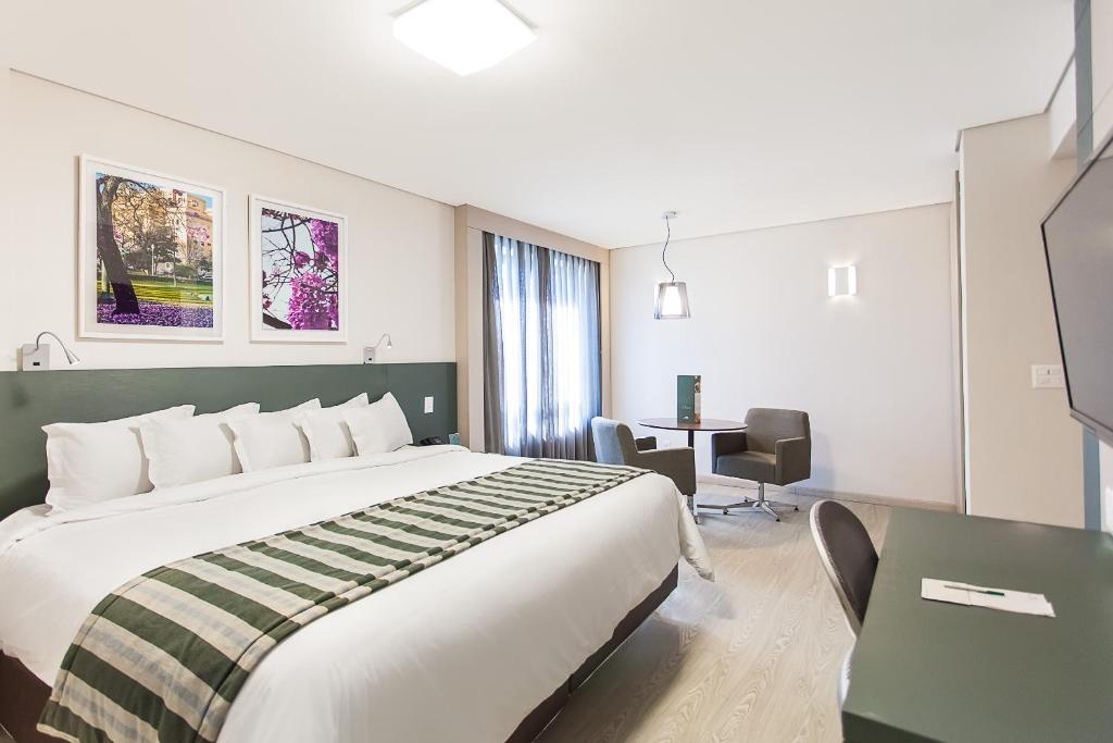 a hotel room with a large bed and a desk at Living Sion in Belo Horizonte