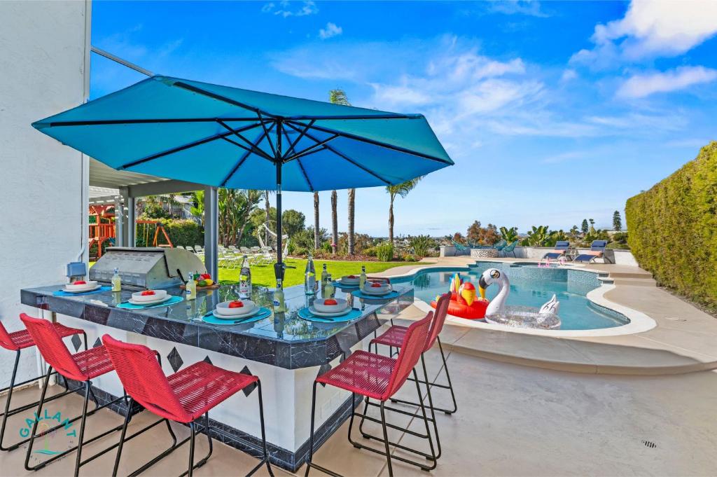 an outdoor bar with red chairs and a blue umbrella at SoCal Gem Pool, Spa, Games, and Scenic Views in Oceanside