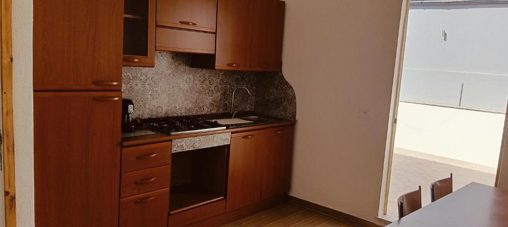a kitchen with wooden cabinets and a stove top oven at Piccola Azzurra bedrooms in Comiso