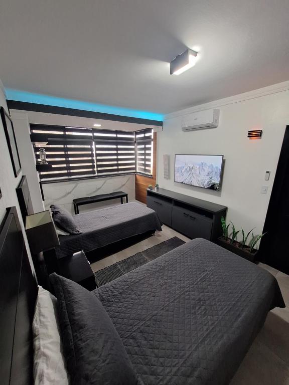 a bedroom with two beds and a tv on the wall at Frente Mar Santos 130 m2 in Santos