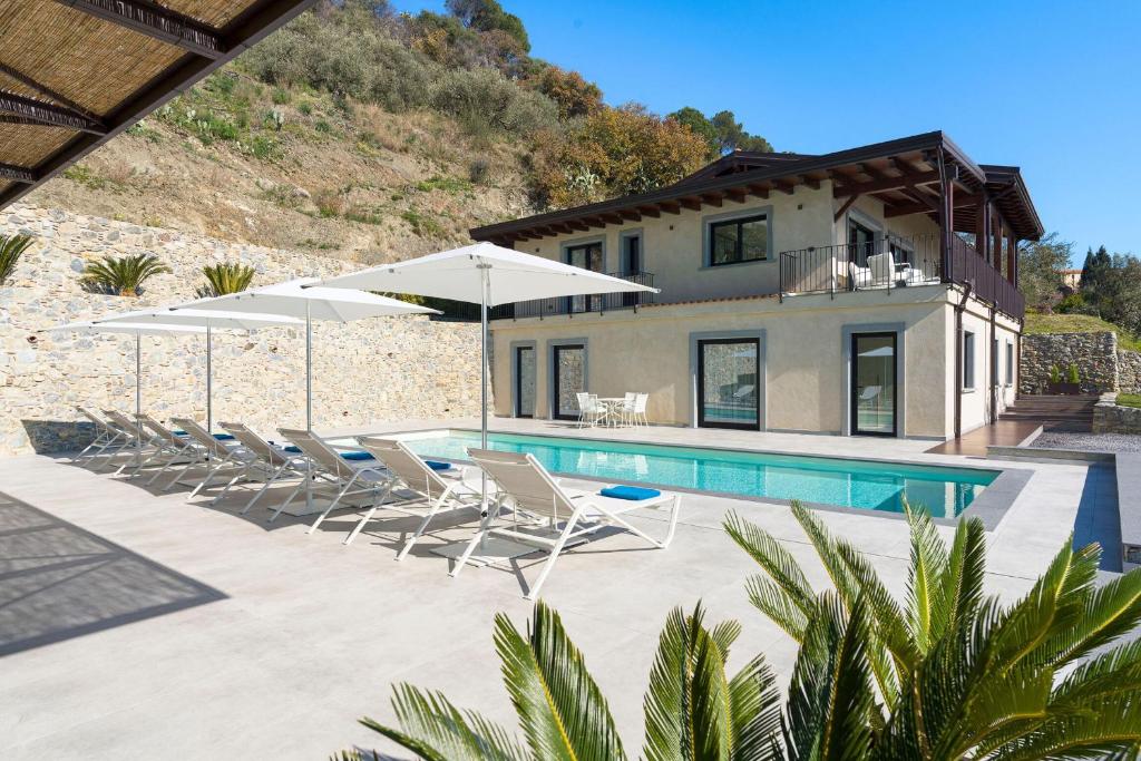 a house with a swimming pool with chairs and umbrellas at Villa Zagara in Savoca