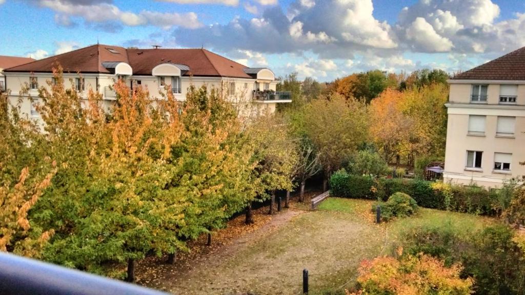 - une vue sur une cour arborée et un bâtiment dans l'établissement Appartement pour 4 personnes - Accès direct Disneyland & Paris - Proche Gare RER A, à Bussy-Saint-Georges