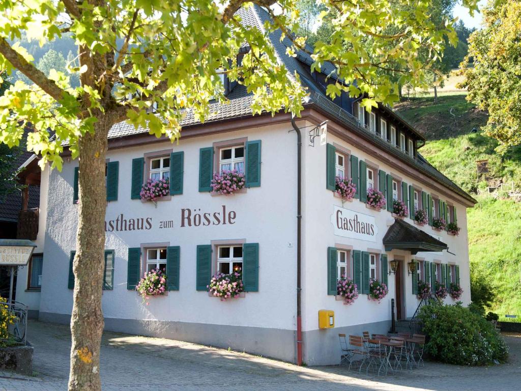 un bâtiment avec des volets verts et des fleurs aux fenêtres dans l'établissement Gasthaus zum Rössle, à Bollschweil