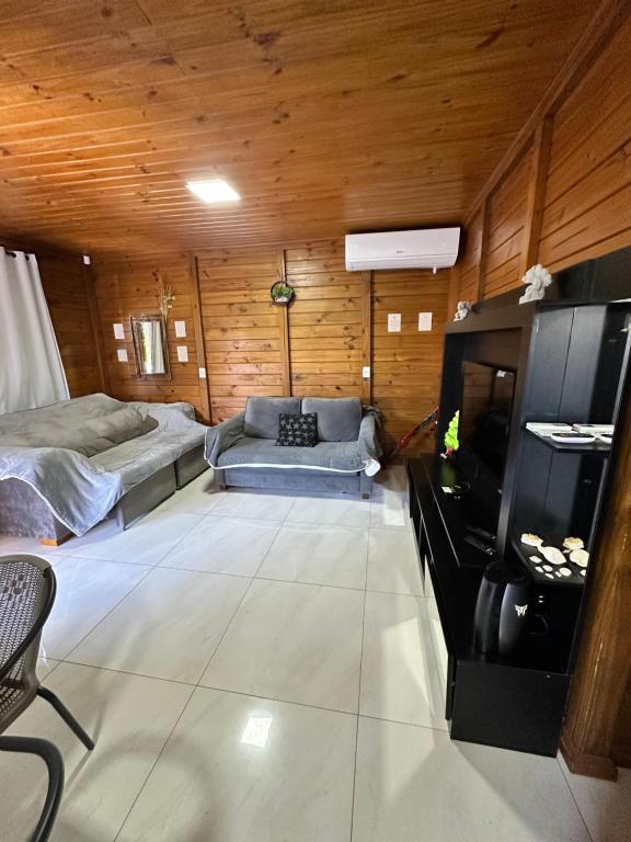 a room with a couch and a bed and a tv at Woodhouse Tranquilidade e Conforto no Paraíso, piscina aquecida e ar condicionado in Alto Paraíso de Goiás