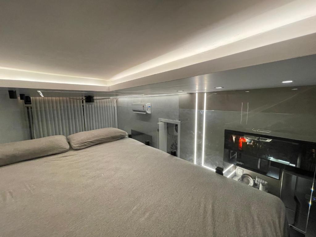 une chambre avec un lit et une télévision au mur dans l'établissement Studio Zona Sul Laranjeiras RJ, à Rio de Janeiro