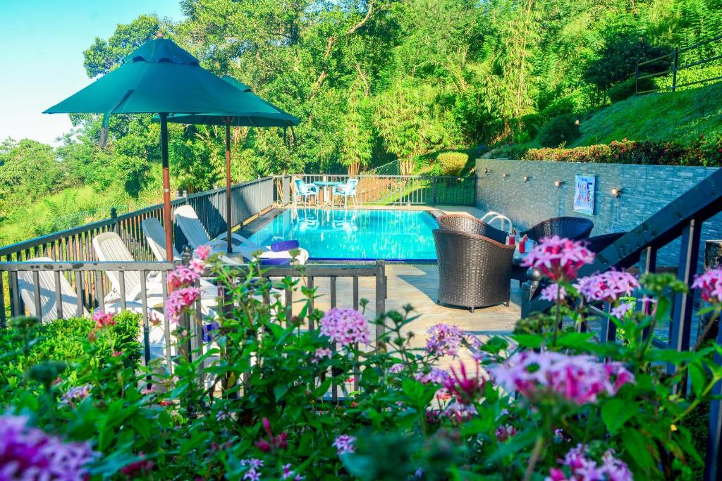 a pool with a table and an umbrella and flowers at Grand Hills kandy in Kandy