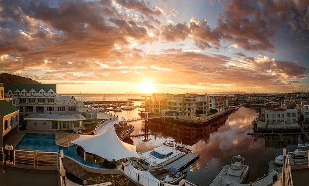 un coucher de soleil sur un port de plaisance avec des bateaux dans l'eau dans l'établissement Krystal Beach Hotel, à Gordons Bay