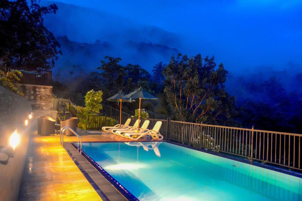 a swimming pool with lounge chairs and an umbrella at Grand Hills kandy in Kandy