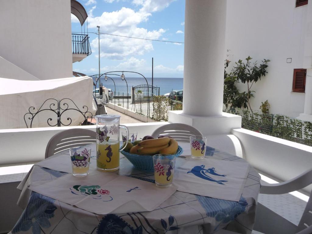 een tafel met een schaal bananen en drankjes op een balkon bij Le Terrazze in Lipari