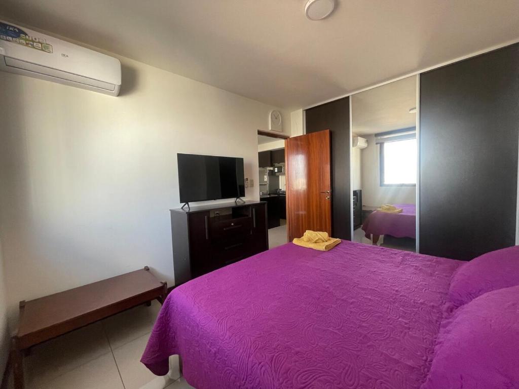 ein Schlafzimmer mit einem lila Bett und einem TV in der Unterkunft Dpto de lujo en Equipetrol, con piscina in Santa Cruz de la Sierra