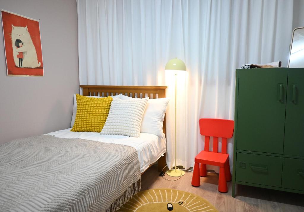 Un dormitorio con una cama y una silla roja. en Stay Onjeong Jamsil Accommodation, en Seúl